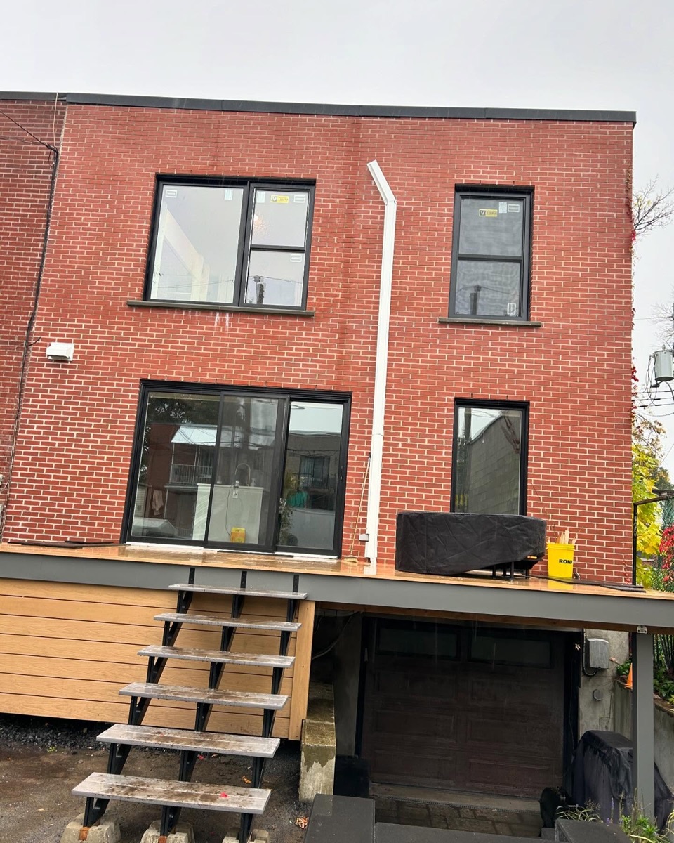 Fenêtres et portes-patio noires neuves sur un duplex en brique rouge