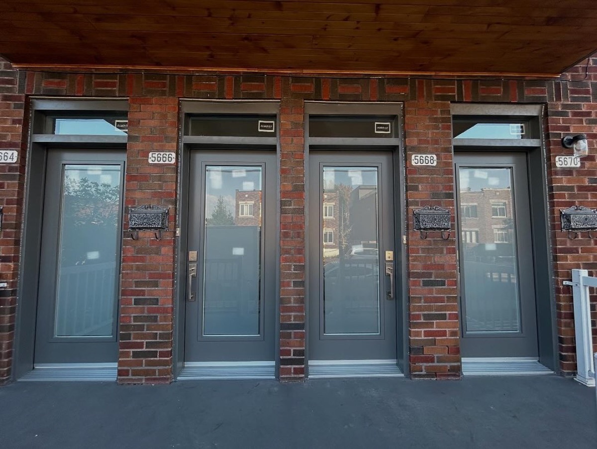 Quatre portes d'entrée neuves gris foncé sur un quadruplex en brique rouge